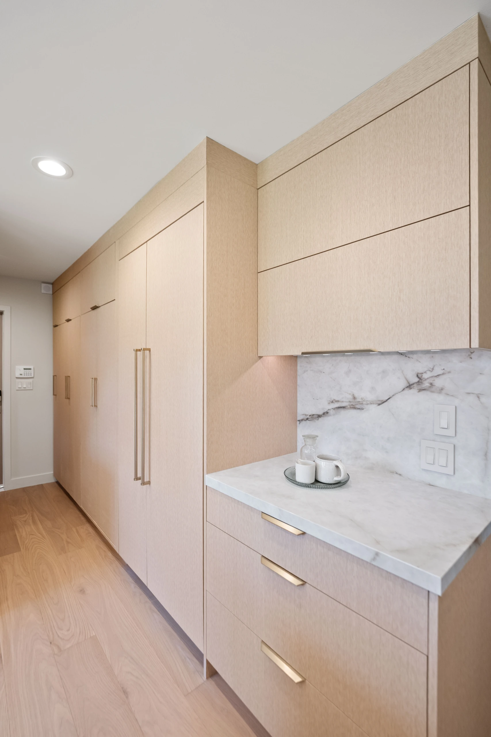 Crystal kitchen with flat-panel light oak cabinets, brass pulls and a marble backsplash