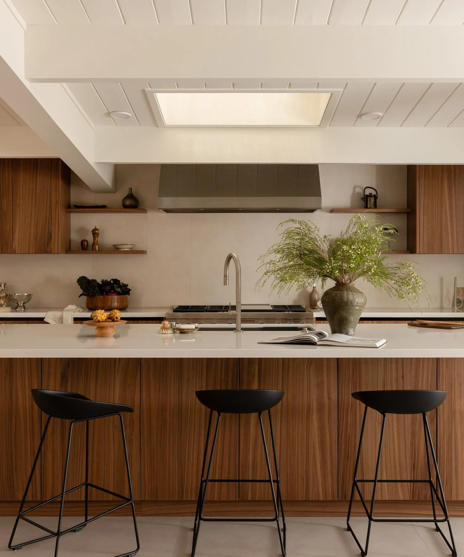 Eichler kitchen with walnut island under a painted tongue and groove ceiling and skylight