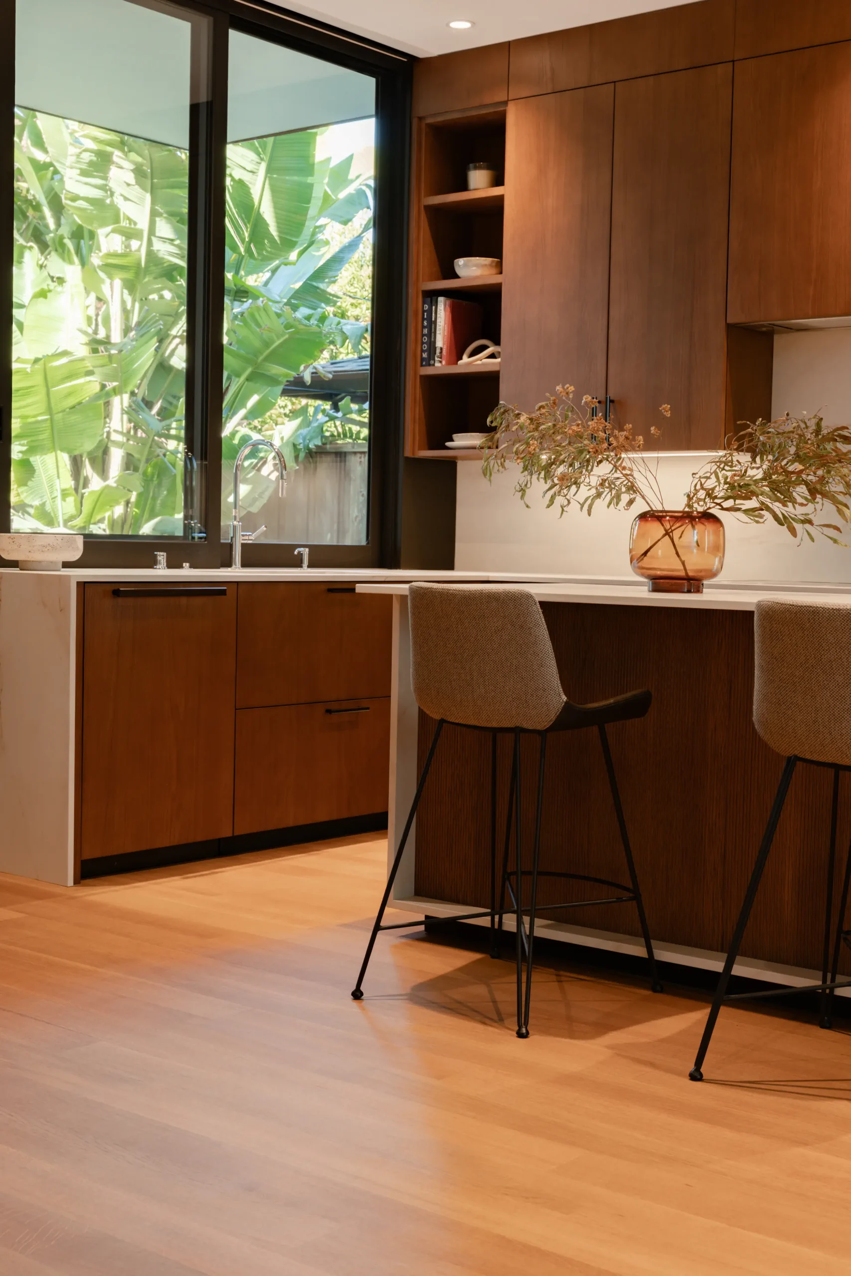 DOCA kitchen Cabinets highlighting warmth through wood and minimalist modern design with clear windows with table and chairs