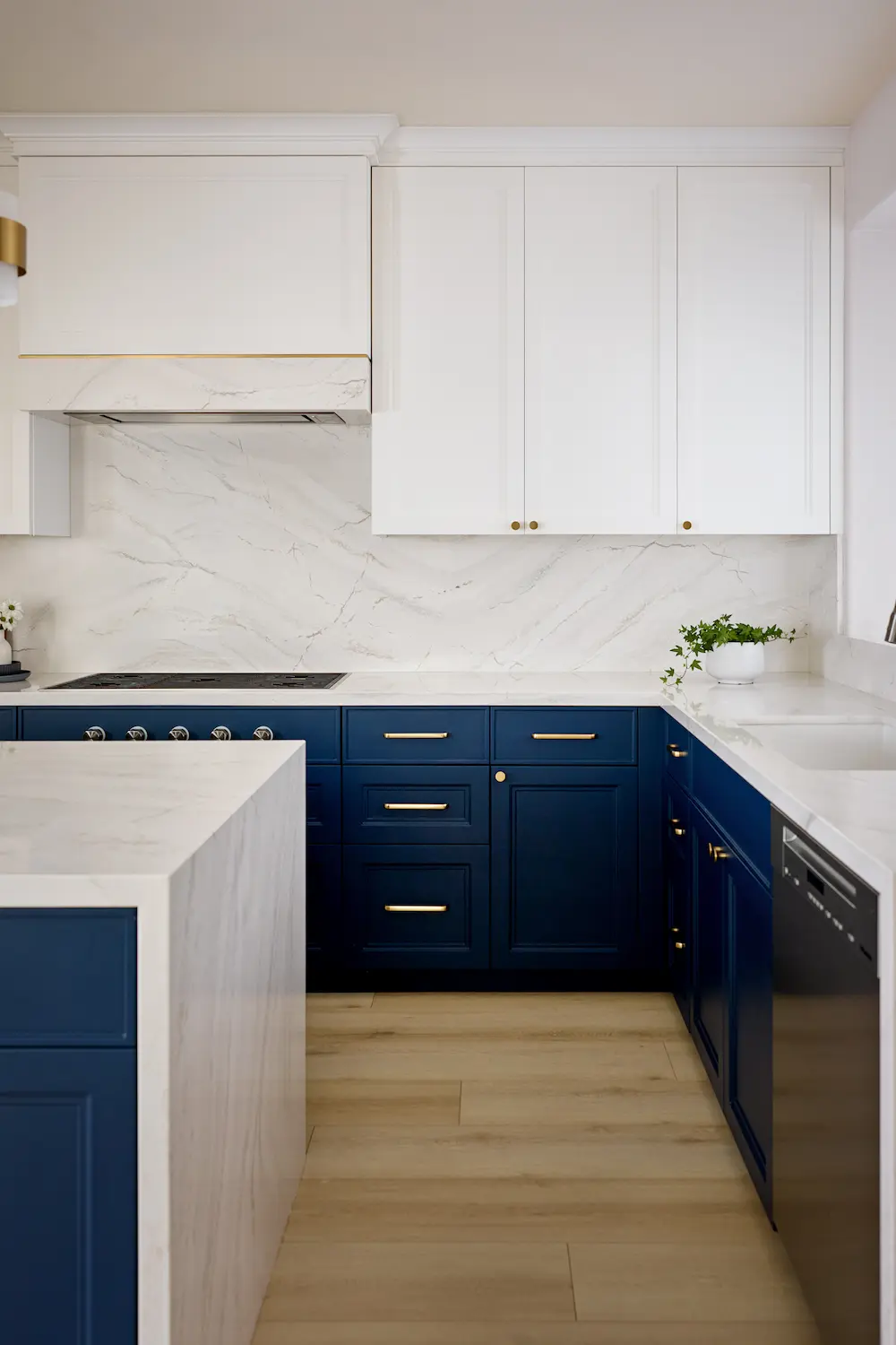 L-shaped navy kitchen cabinetry with a marble backsplash and black dishwasher