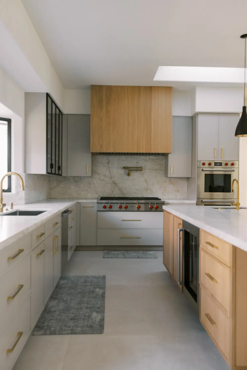 Gray cabinets, an oak range hood and an oak island with a beverage fridge