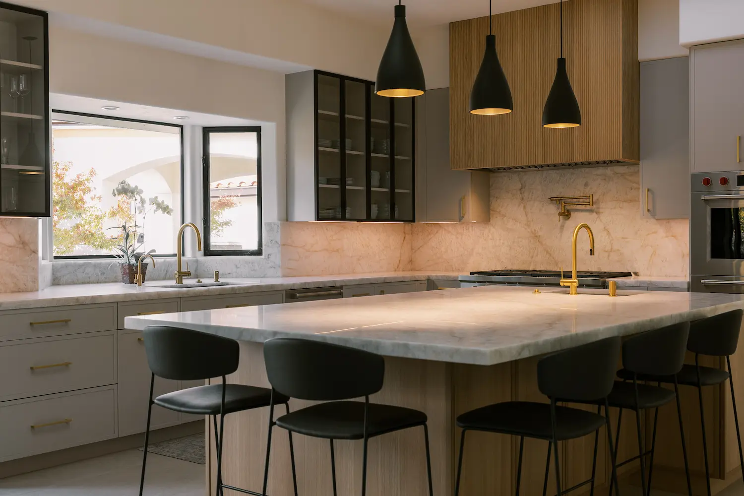 Two-tone kitchen with gray and oak cabinets, a veined stone island and black pendants