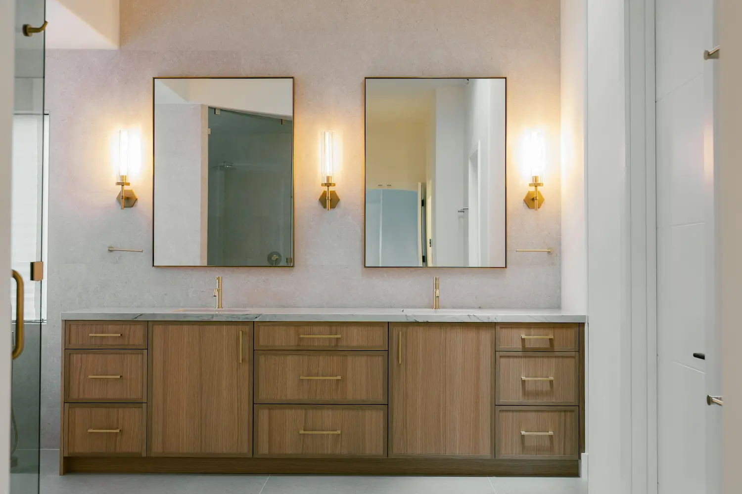 Floating wood double vanity with brass pulls, two mirrors and brass wall sconces