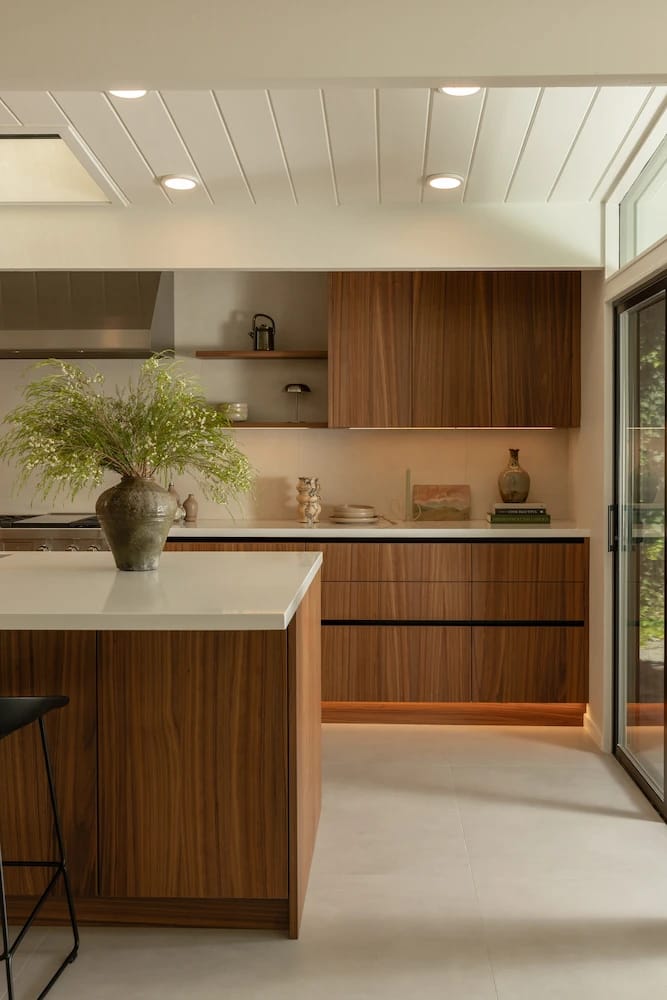 Kitchen island and wall of wood slab cabinets beneath a white plank Eichler ceiling