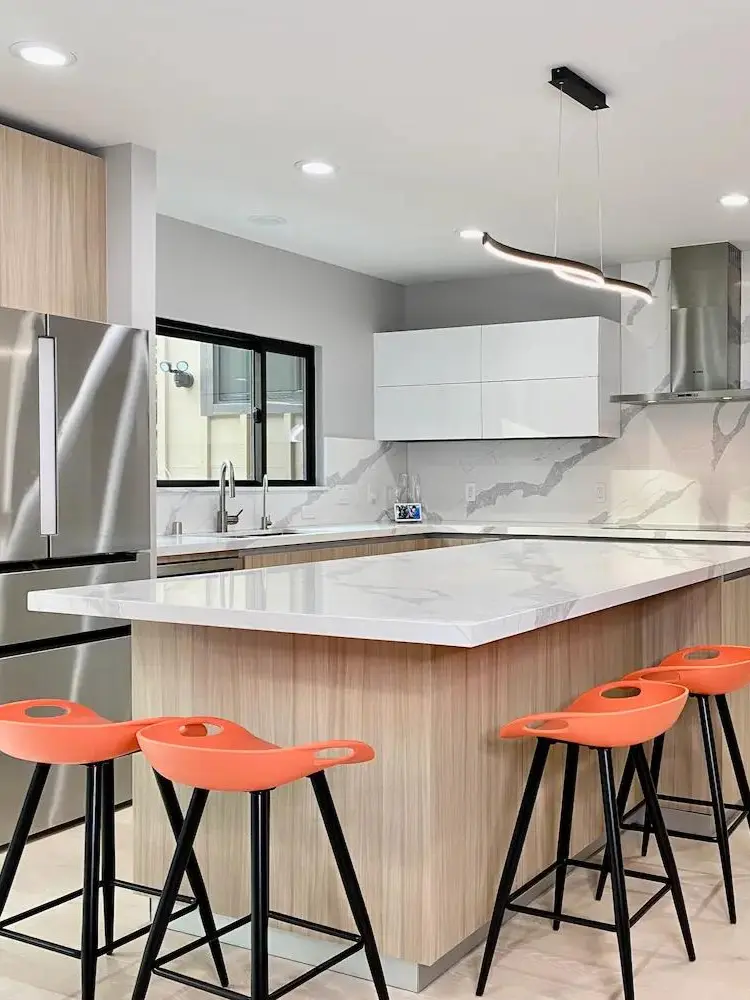 Mid-century modern kitchen featuring a stylish island, stainless steel appliances, and vibrant orange seating