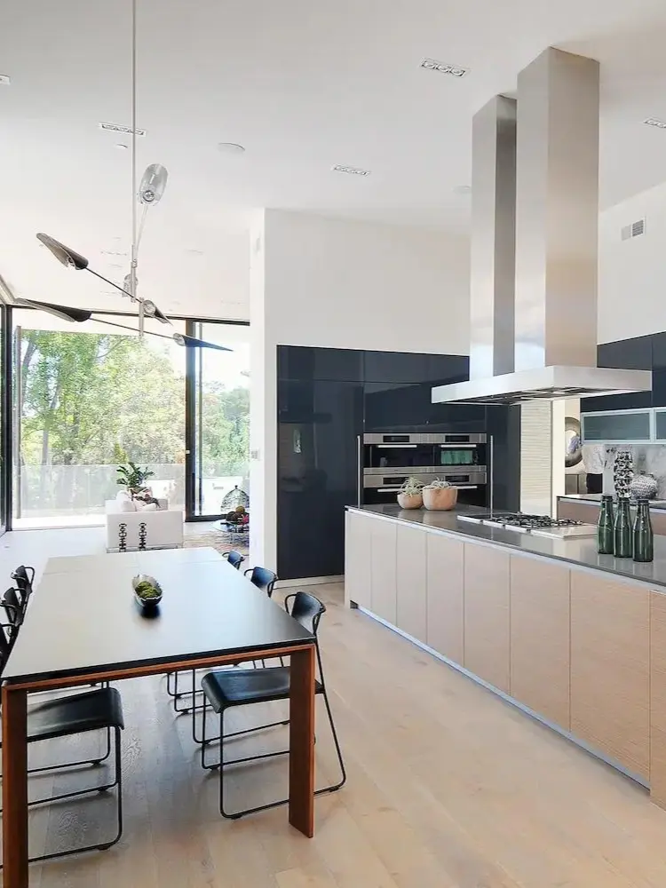 Luxurious kitchen showcasing a blend of black and wood tones, with a central island and floor-to-ceiling windows inviting natural light