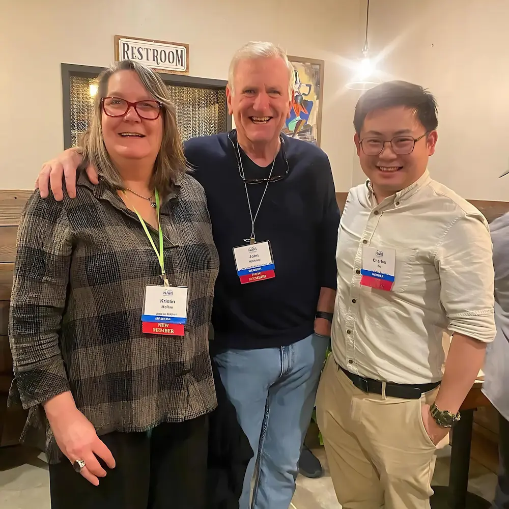 Three guests with name badges smiling together at an industry networking event