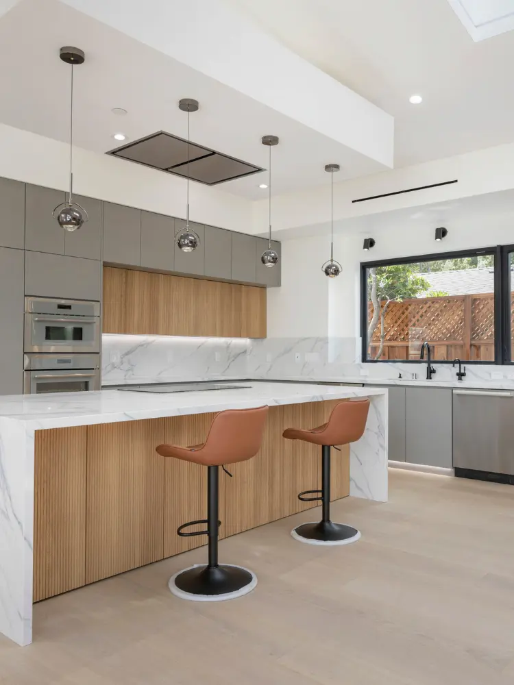 Elegant kitchen design with light wood cabinetry, modern pendant lighting, and seamless marble finishes