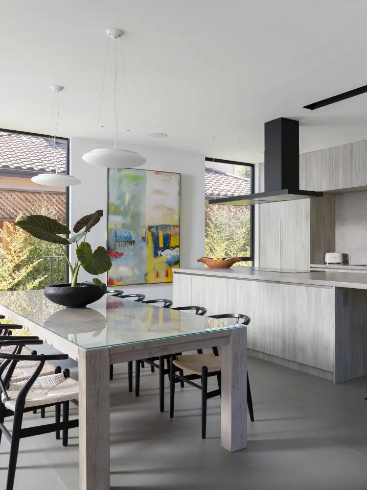Modern kitchen design featuring a combination of clean lines, elegant cabinetry, and a functional dining area with a view of natural surroundings