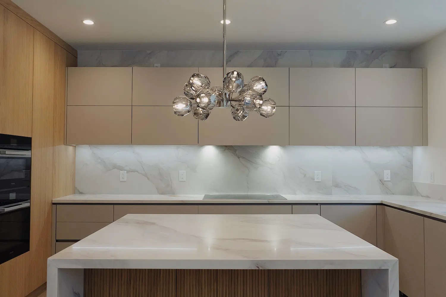 Contemporary DOCA kitchen with flat taupe cabinets and a sculptural chandelier