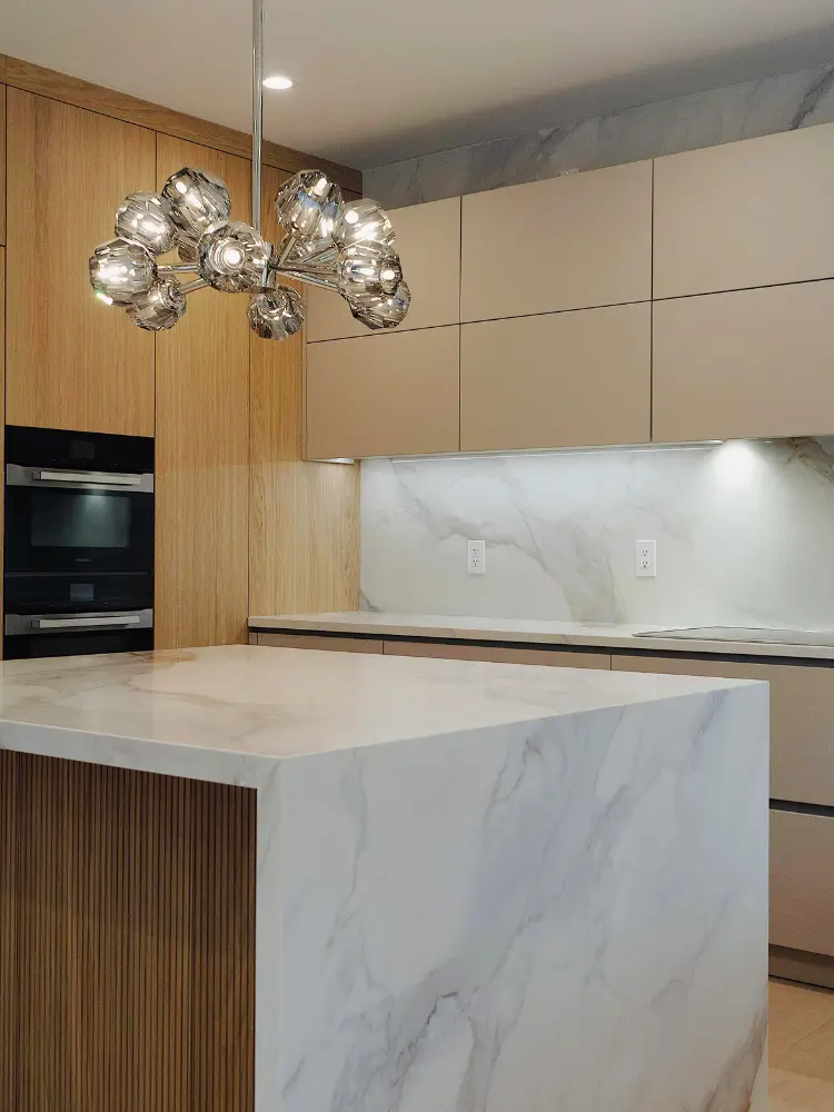 Stunning contemporary kitchen featuring DOCA cabinetry, marble surfaces, and a statement chandelier