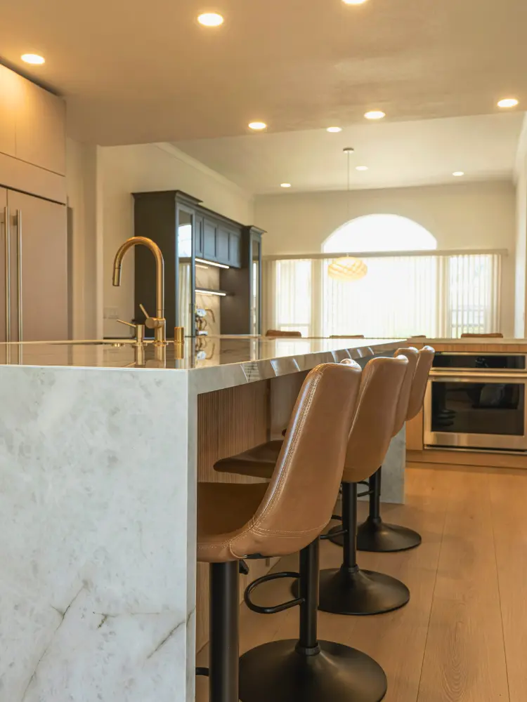Luxury kitchen featuring a marble waterfall island, gold fixtures, and high-end cabinetry