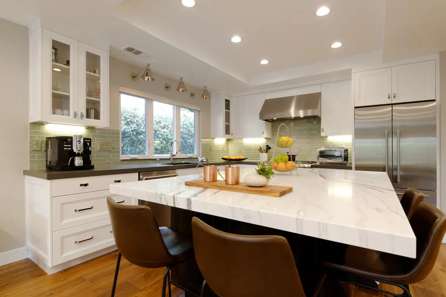 Transitional kitchen with marble island, stainless steel appliances, and light green subway tile backsplash