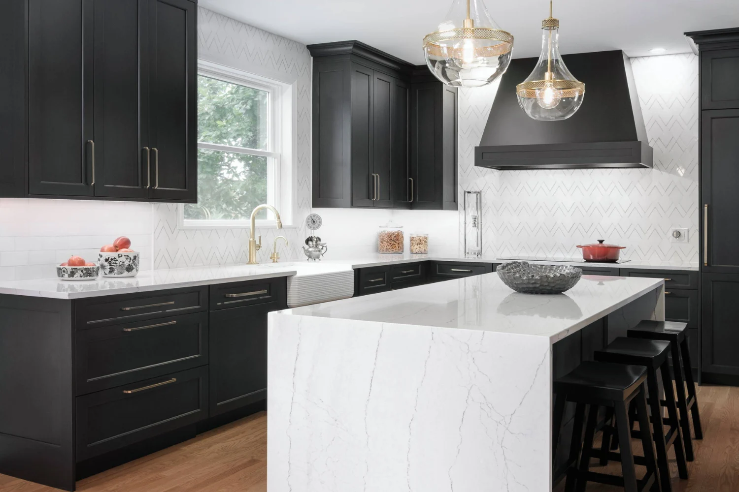 Black and white kitchen design with quartz countertops, gold hardware, and herringbone backsplash for a bold, modern look