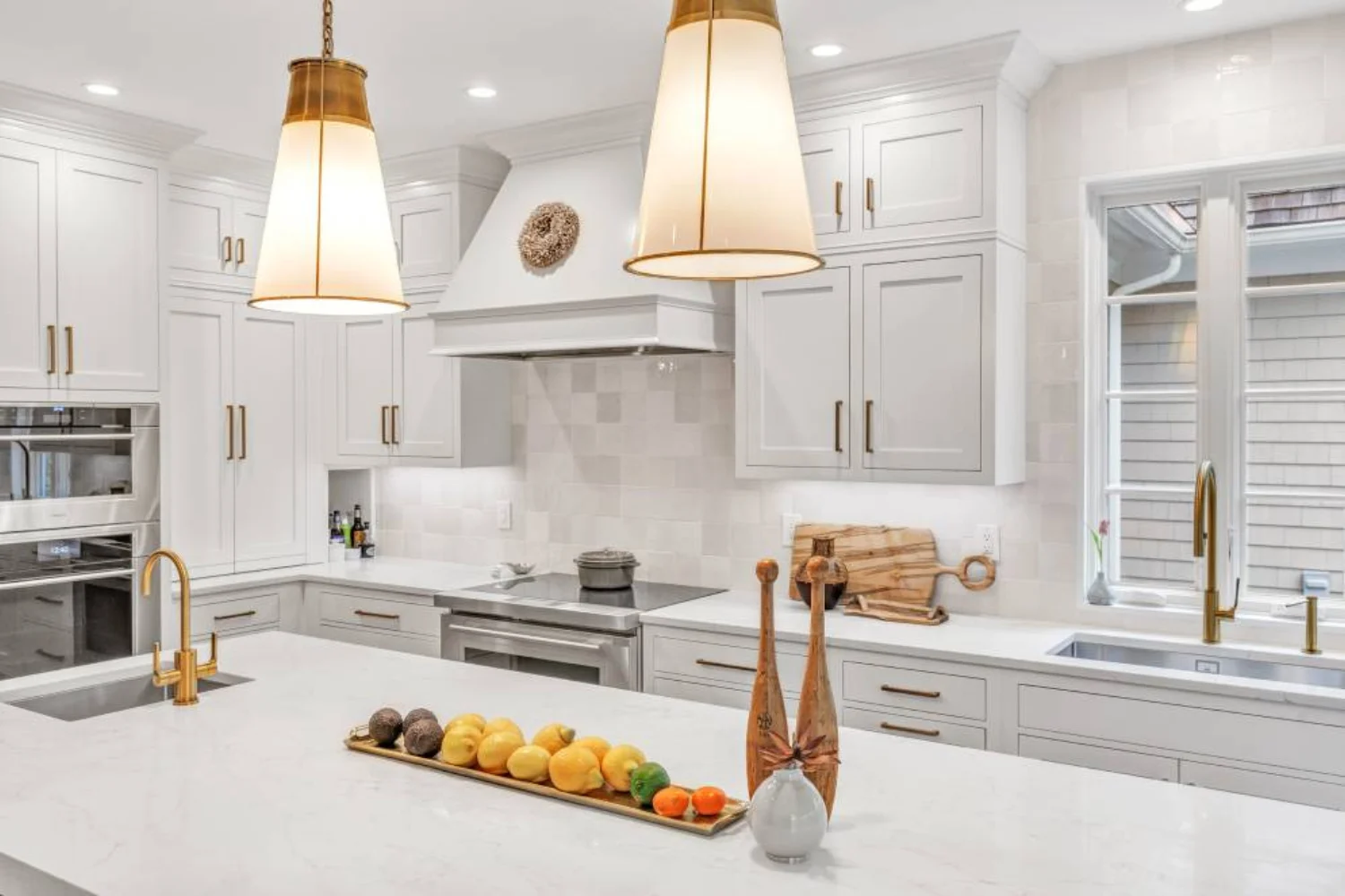 Transitional kitchen with soft gray cabinets, white quartz countertops, and brass pendant lighting over a central island