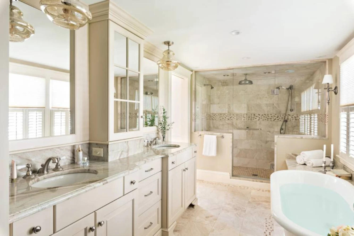 Luxurious bathroom with creamy white cabinetry, double vanities, glass shower enclosure, and polished marble finishes