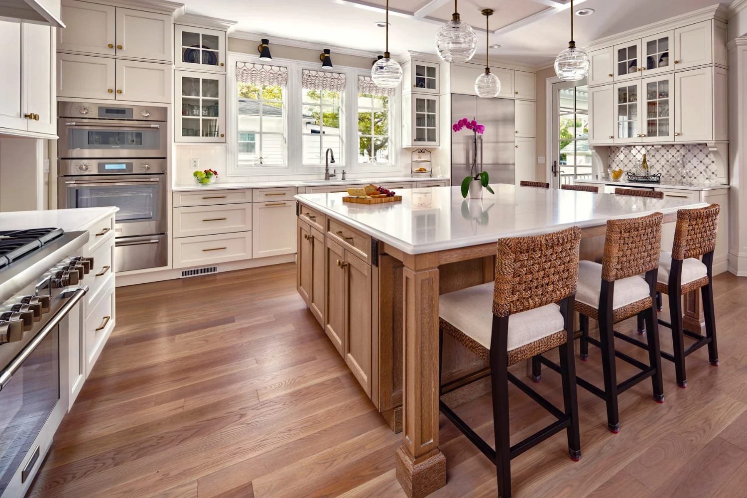 Traditional kitchen with two-tone cabinetry, light oak island, and globe pendant lighting over a polished quartz countertop
