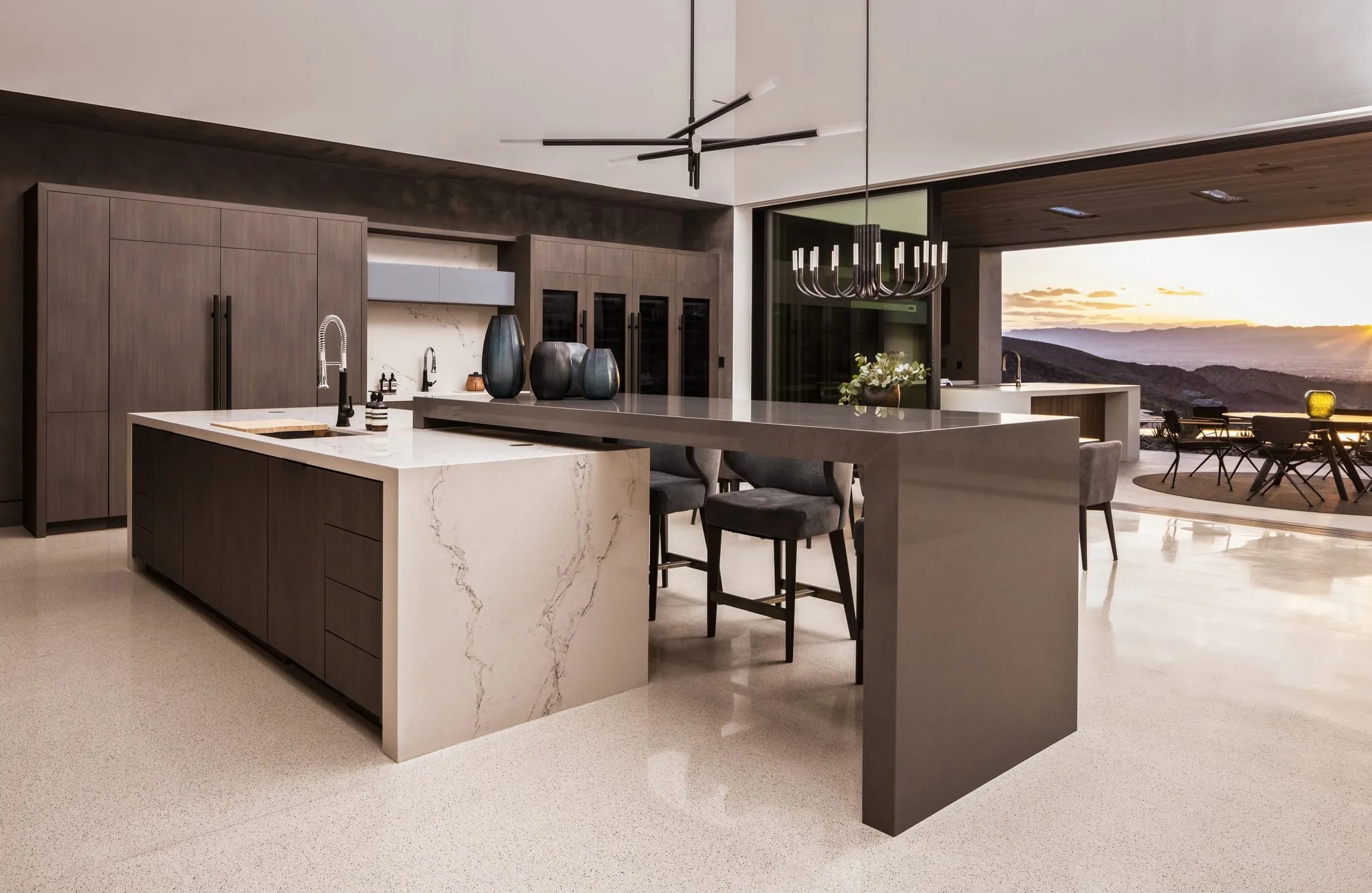 Contemporary Wood-Mode kitchen with a stone waterfall island at dusk