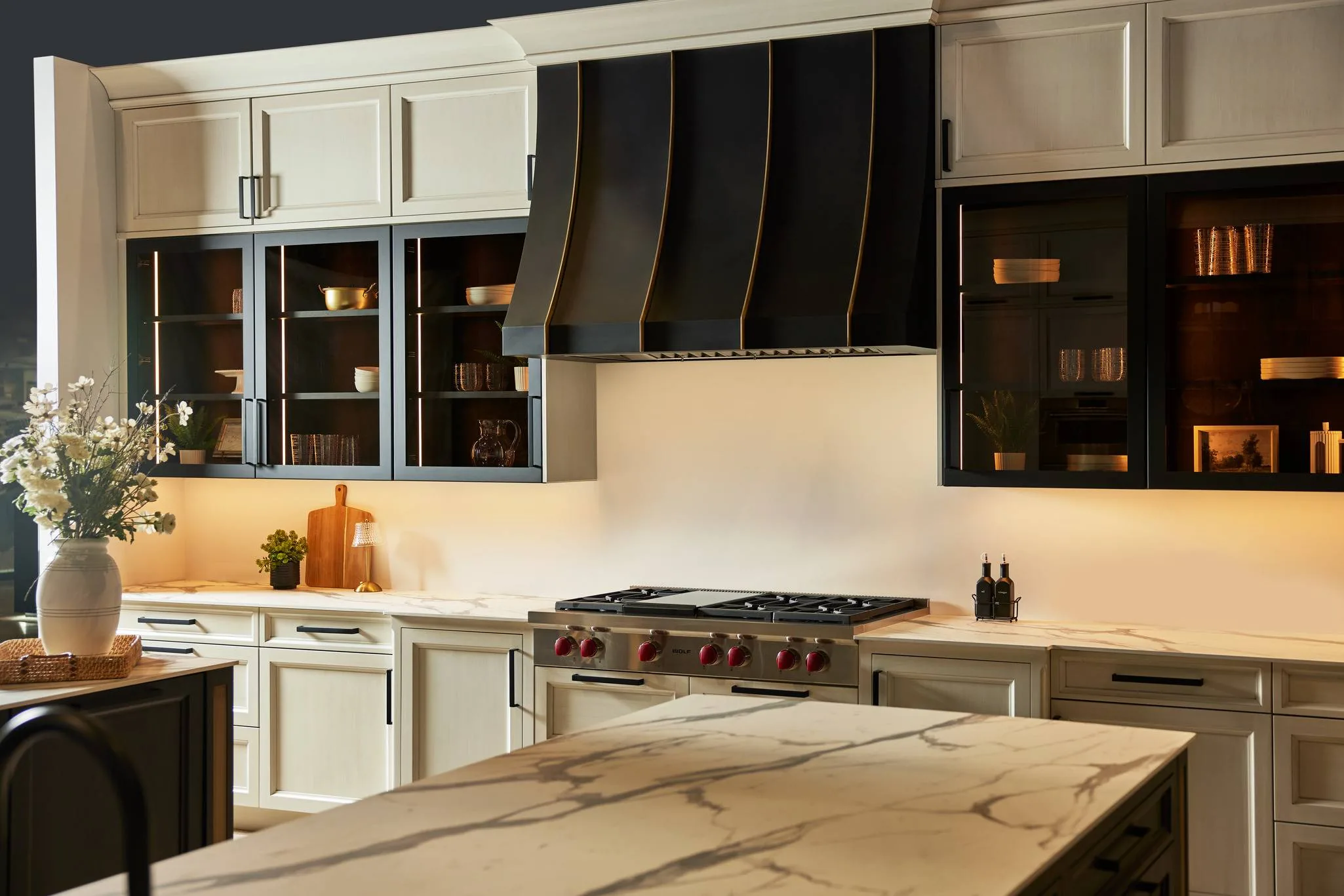Wood-Mode kitchen with painted cabinets, a black hood and glass wall cabinets