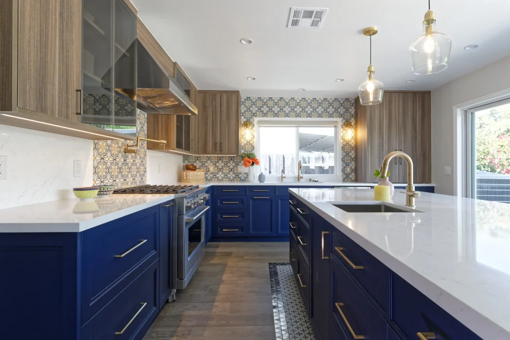 Bold kitchen with navy blue lower cabinets, wood upper cabinets, patterned tile backsplash, and gold accents.