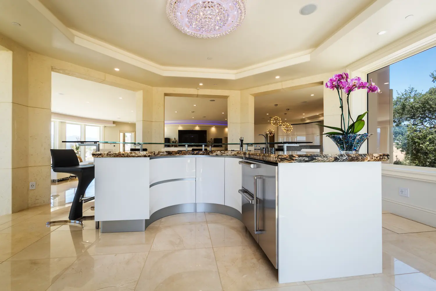 Spacious kitchen with a central island, glossy white cabinetry, and stylish pendant lighting, offering a blend of modern design and functionality