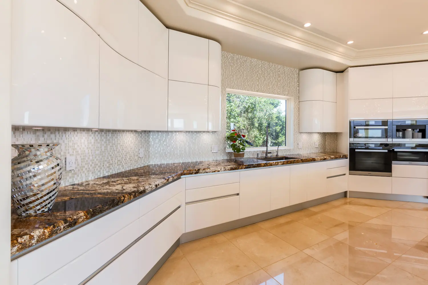 High-end kitchen with curved design elements, glossy white cabinetry, and a central island, offering a panoramic view and modern elegance