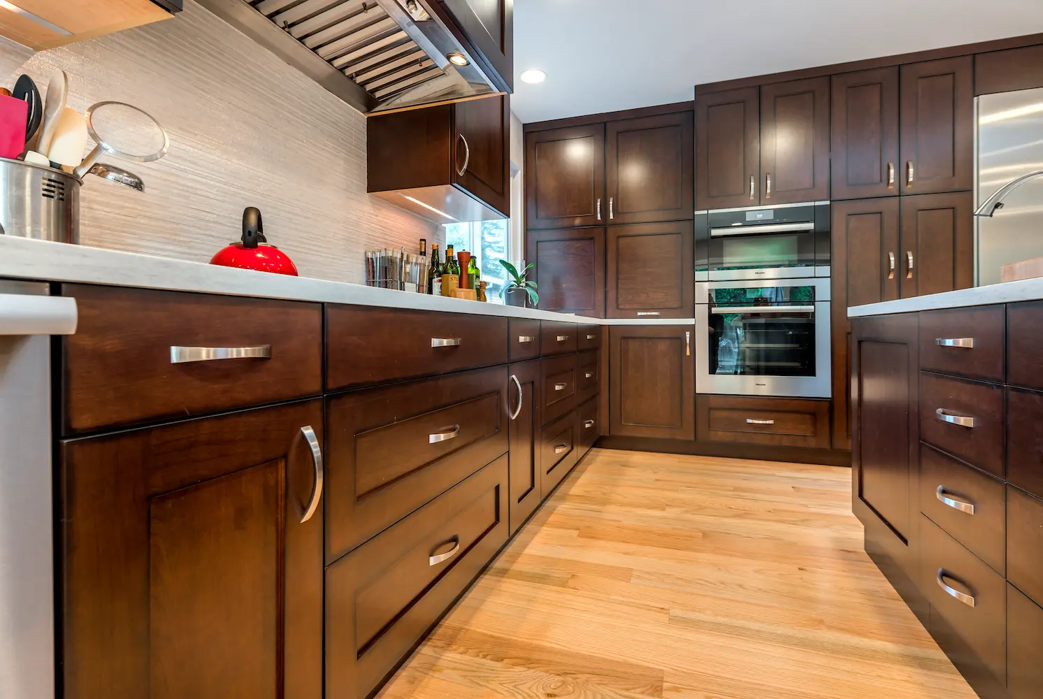 Kitchen island with dark wood cabinets, white countertop, and stainless steel faucet, viewed from a low angle