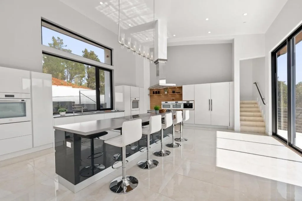 Modern luxury kitchen with sleek white cabinetry, large island, and high-end appliances.