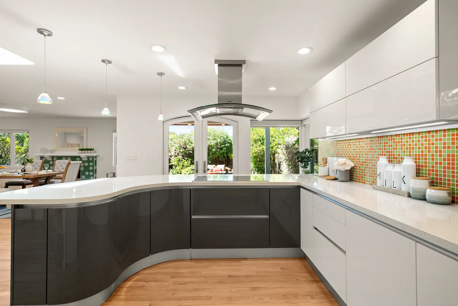Stylish kitchen with a curved island and vibrant mosaic tile backsplash, blending mid-century modern aesthetics